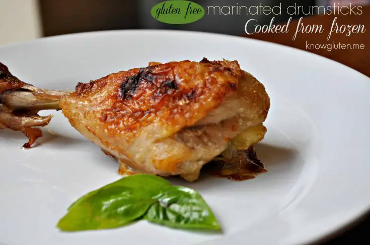 A cooked chicken drumstick on a plate with basil leaves beside it.