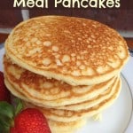 a closeup of gluten free cornmeal pancakes on a plate with a strawberry