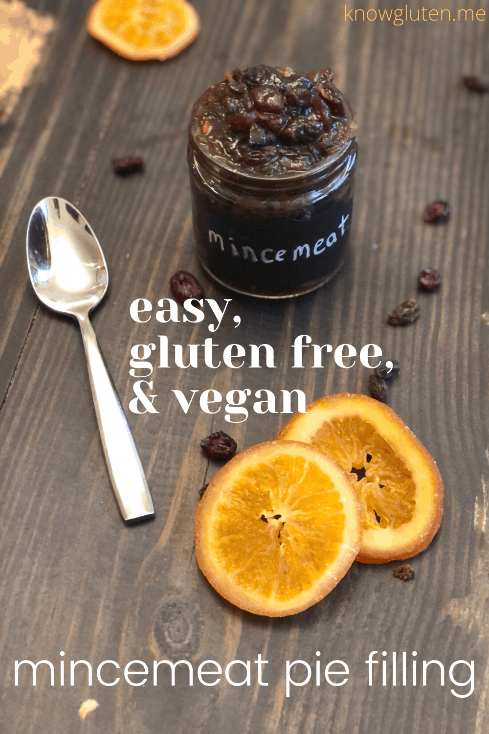 Easy gluten free vegan mincemeat pie filling from knowgluten.me in a small jar on a table with candied orange slices, raisins, and a spoon