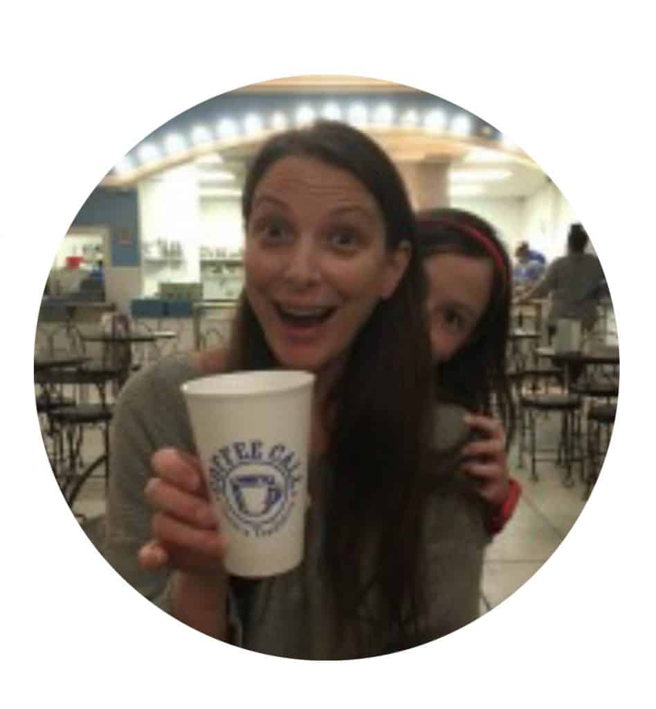 Jodi holding a cup of coffee with Dagny peeking out from behind her head.