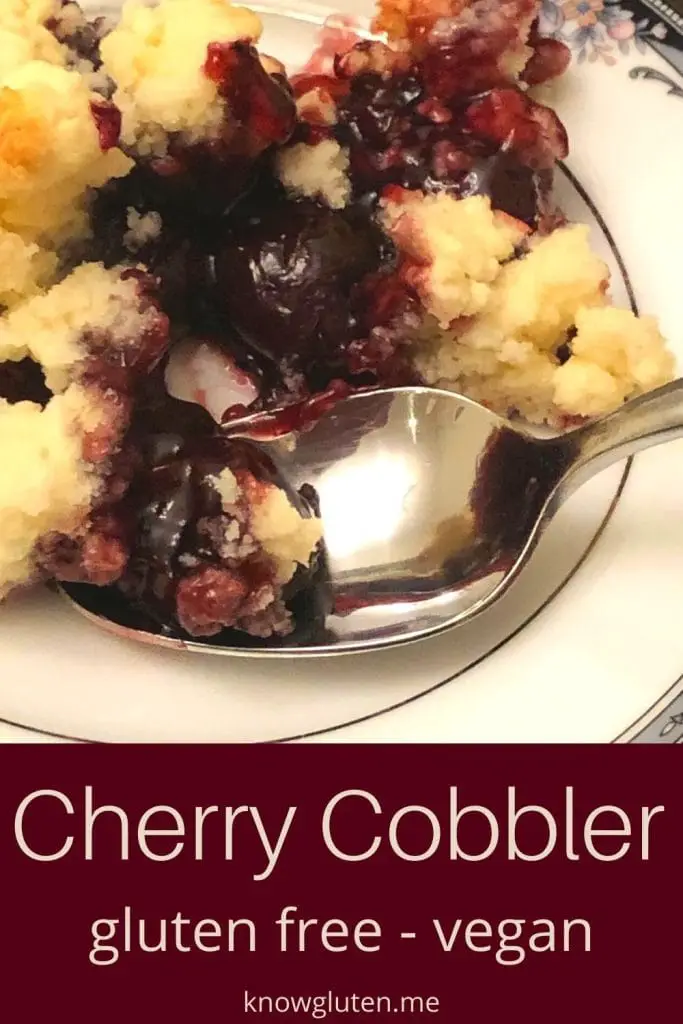 A closeup of gluten free cherry cobbler on a china plate with a spoon.